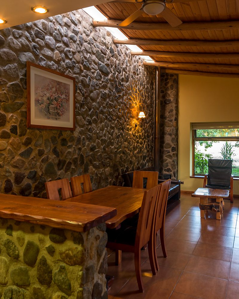 Interior de cabaña de Olmué Natura con muro de piedra y madera nativa