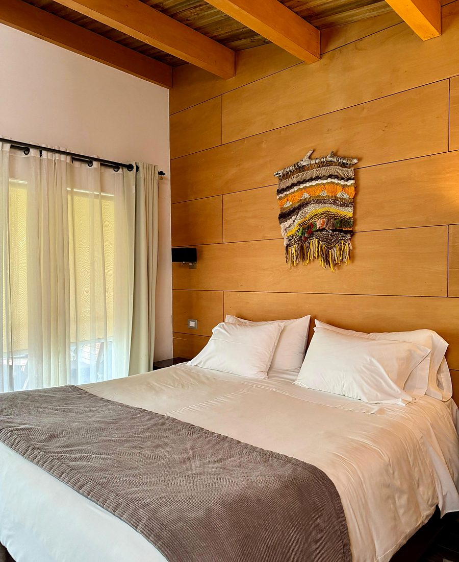 Dormitorio de suite en Olmué Natura con cabecera de madera nativa