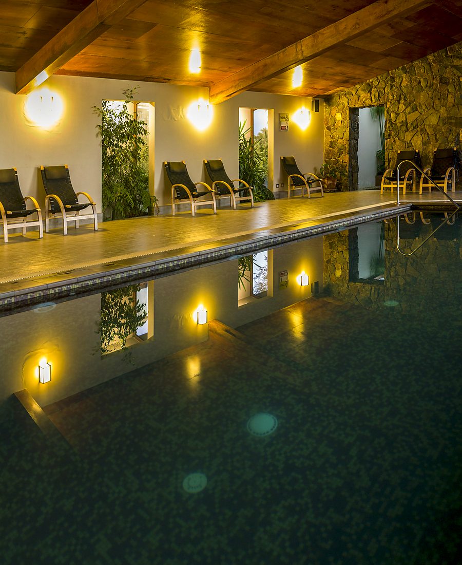 Piscina temperada techada del spa de Olmué Natura, rodeada de piedra y vegetación
